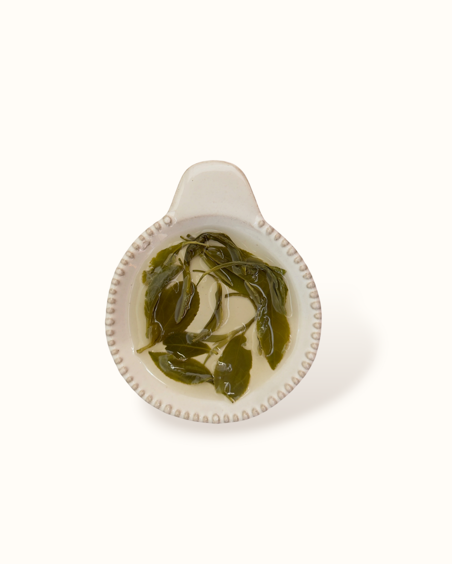 Close-up of Mao Feng tea leaves in a ceramic bowl