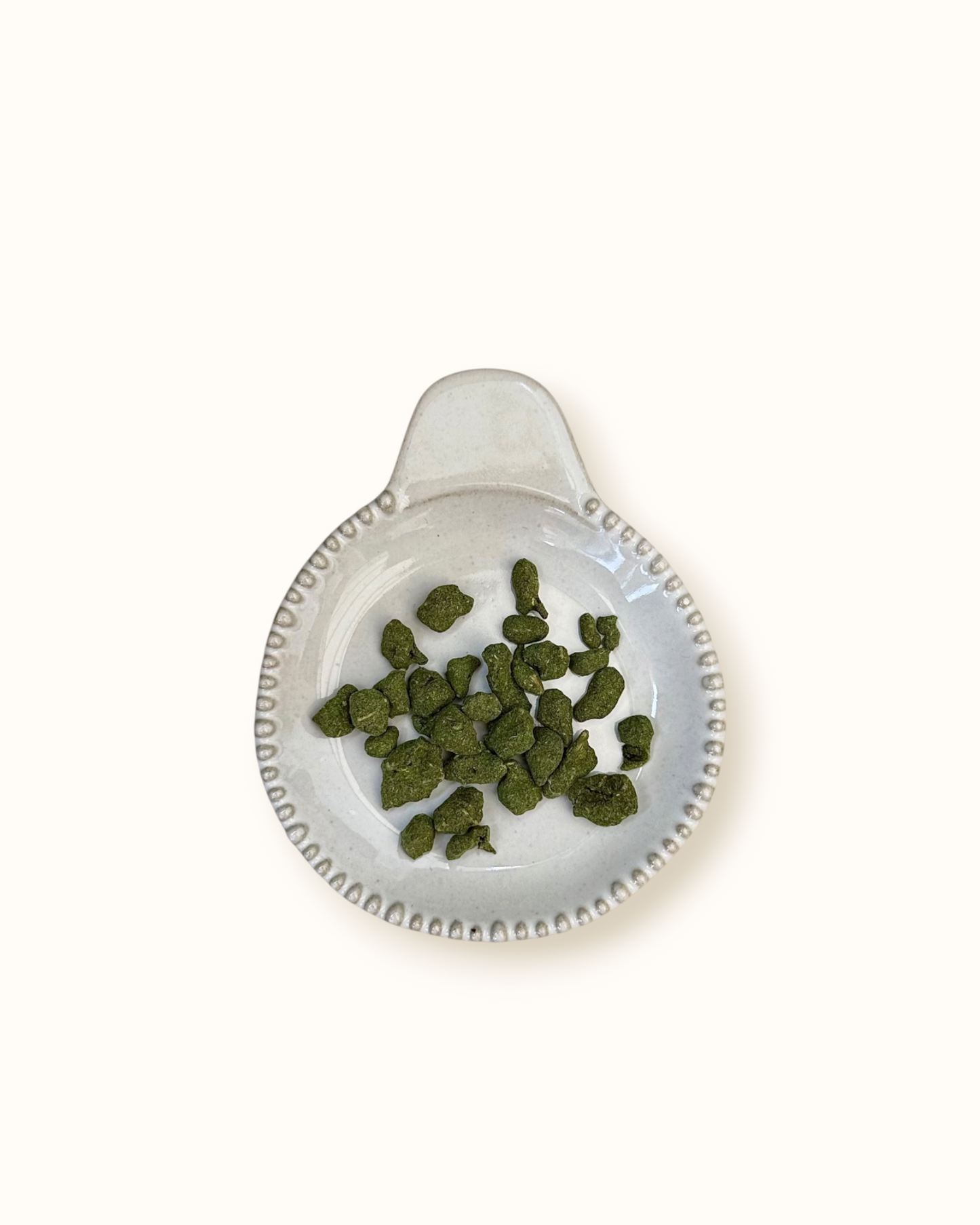 Detailed close-up of dry Ginseng Oolong rolled tea leaves on a small ceramic dish
