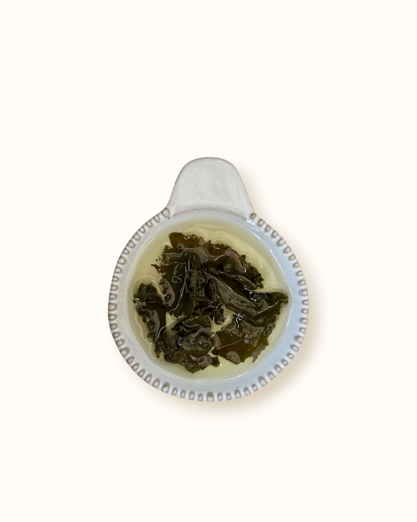 Detailed close-up of infused Ginseng Oolong tea leaves in a ceramic dish after brewing
