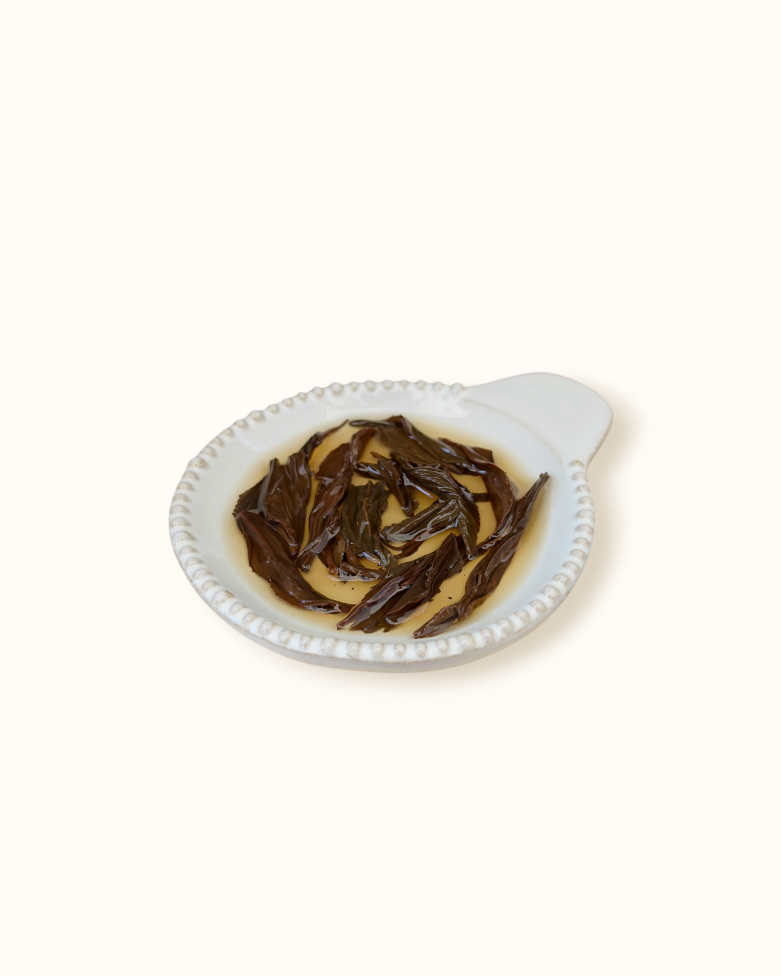 Detailed close-up of infused Lapsang Souchong black tea leaves in a ceramic dish after brewing
