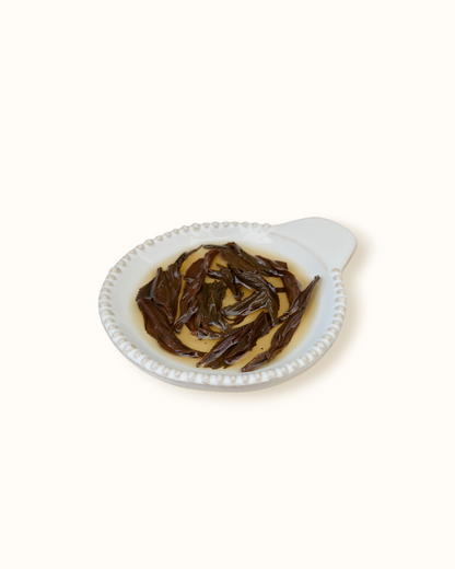 Detailed close-up of infused Lapsang Souchong black tea leaves in a ceramic dish after brewing
