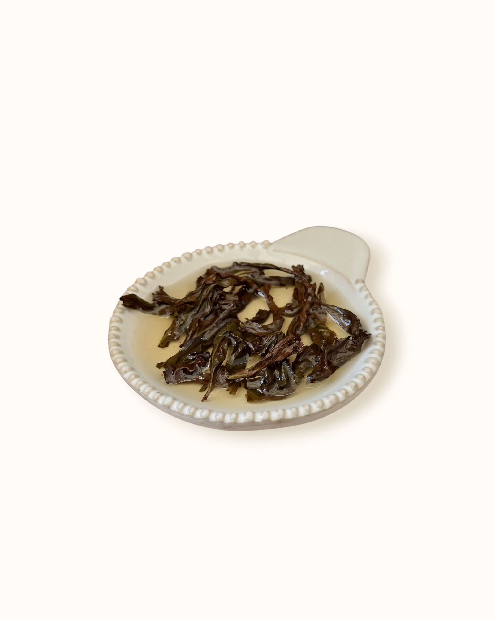 Detailed close-up of infused Da Hong Pao oolong tea leaves in a ceramic dish after brewing
