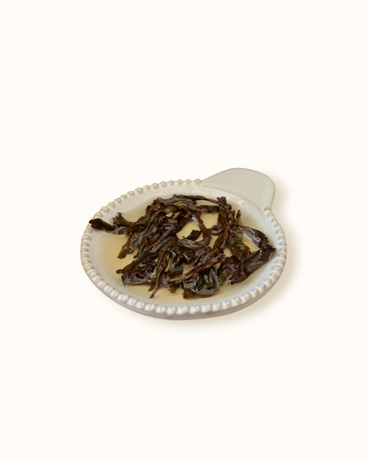 Detailed close-up of infused Da Hong Pao oolong tea leaves in a ceramic dish after brewing
