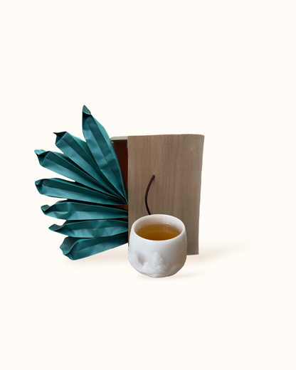 Open White Peony white tea birch wood tea box with teal sachets and amber-golden tea liquor in a white ceramic tea cup
