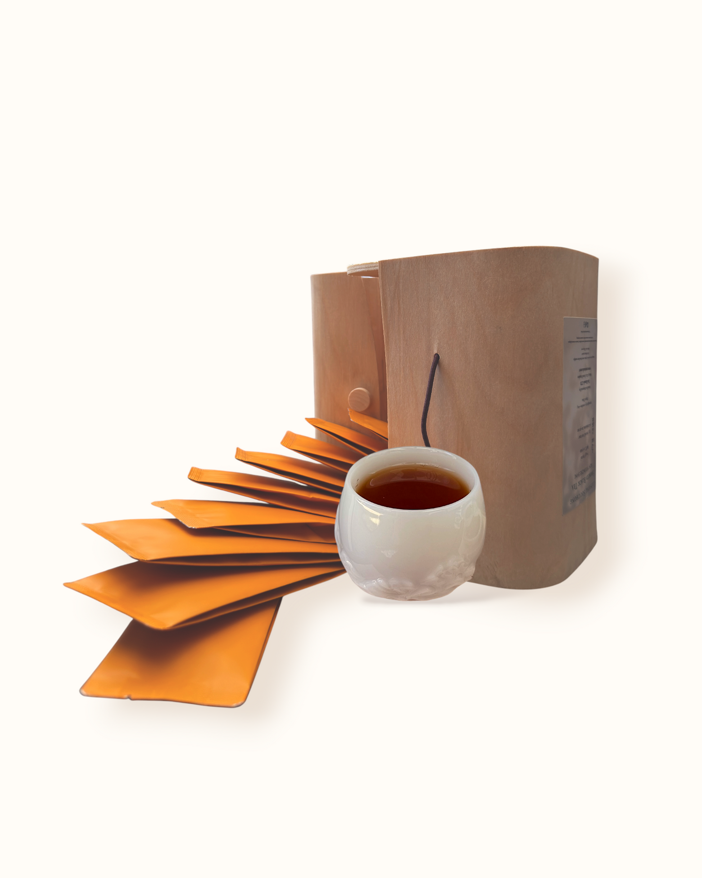 Open Lapsang Souchong black tea birch wood tea box with orange sachets and dark amber tea liquor in a white ceramic tea cup
